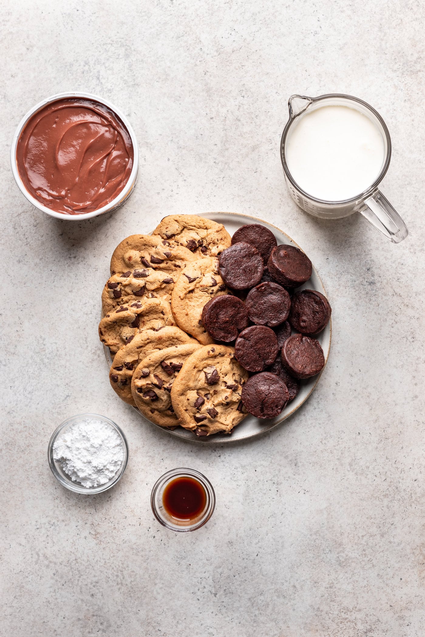 bowls of ingredients like cookies, brownies, chocolate pudding, whipped cream and powdered sugar