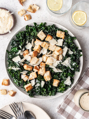 kale caesar salad in a bowl with croutons and cheese on top