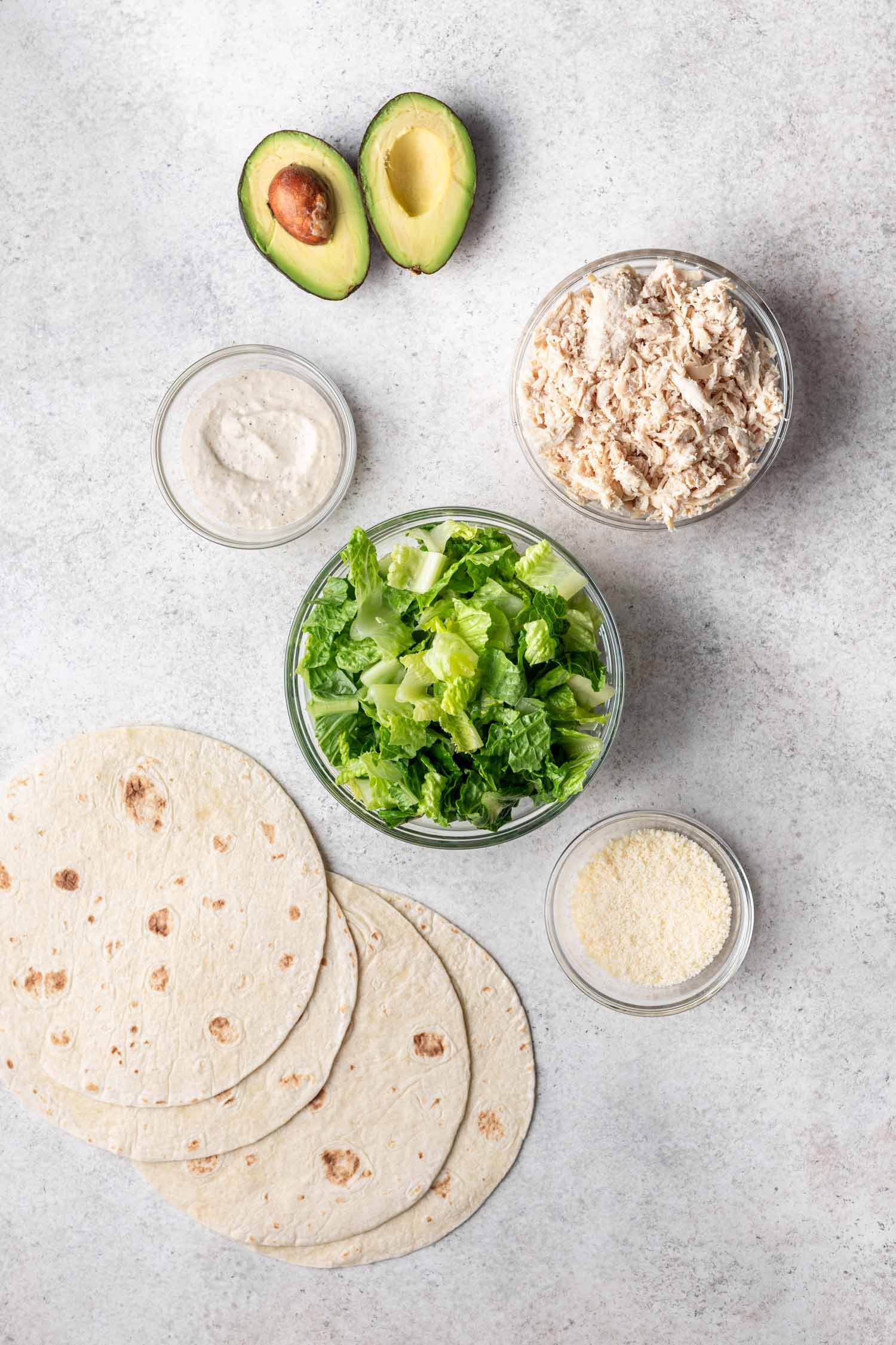 ingredients in bowls such as shredded chicken, lettuce, avocado and tortillas