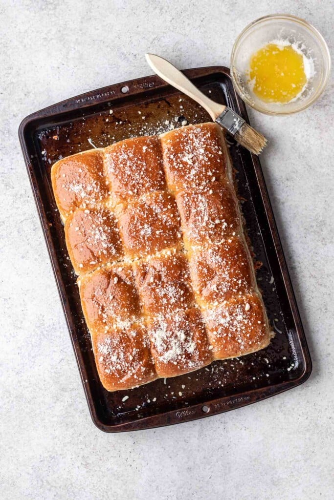 slider buns brushed with oil and parmesan cheese on a sheet pan
