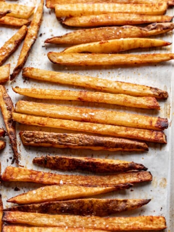 Crispy seasoned French fries on a parchment-lined baking sheet