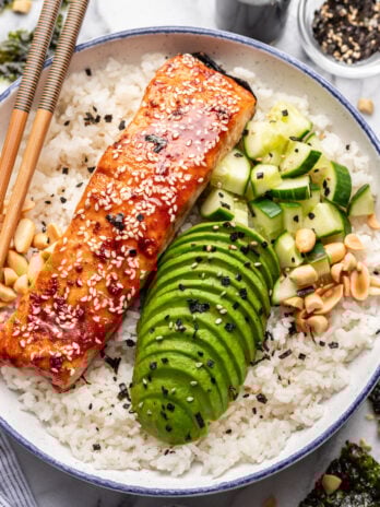 salmon rice bowl with sliced avocado and cucumber