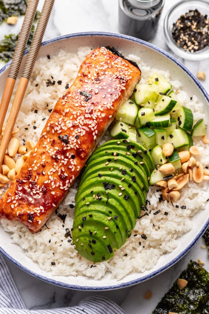 salmon rice bowl with sliced avocado and cucumber