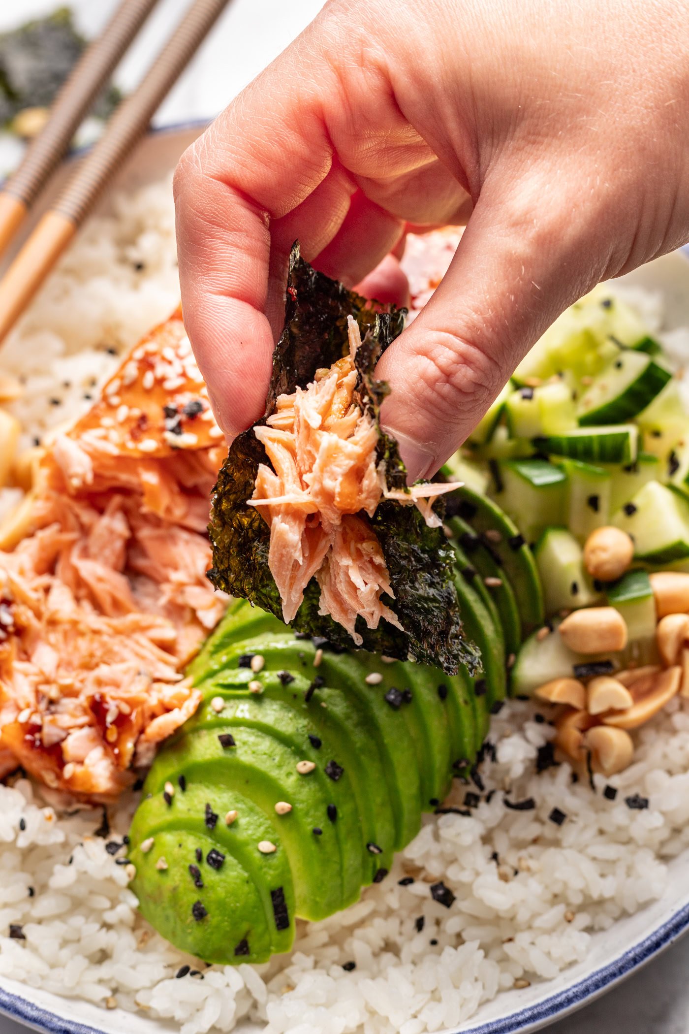 Fresh salmon on rice with avocado, cucumber, and seaweed, served as a salmon rice bowl