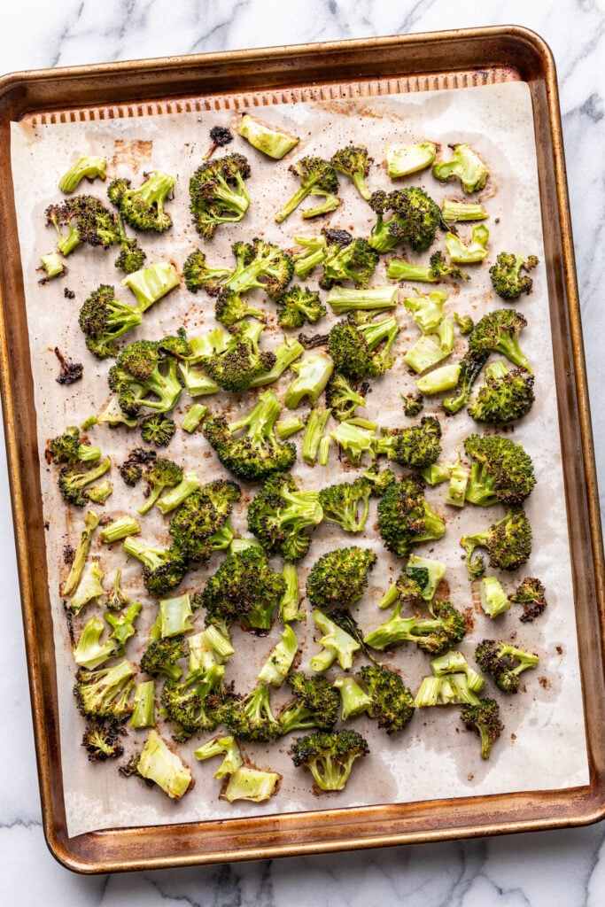 roasted broccoli florets on a parchment lined sheet pan