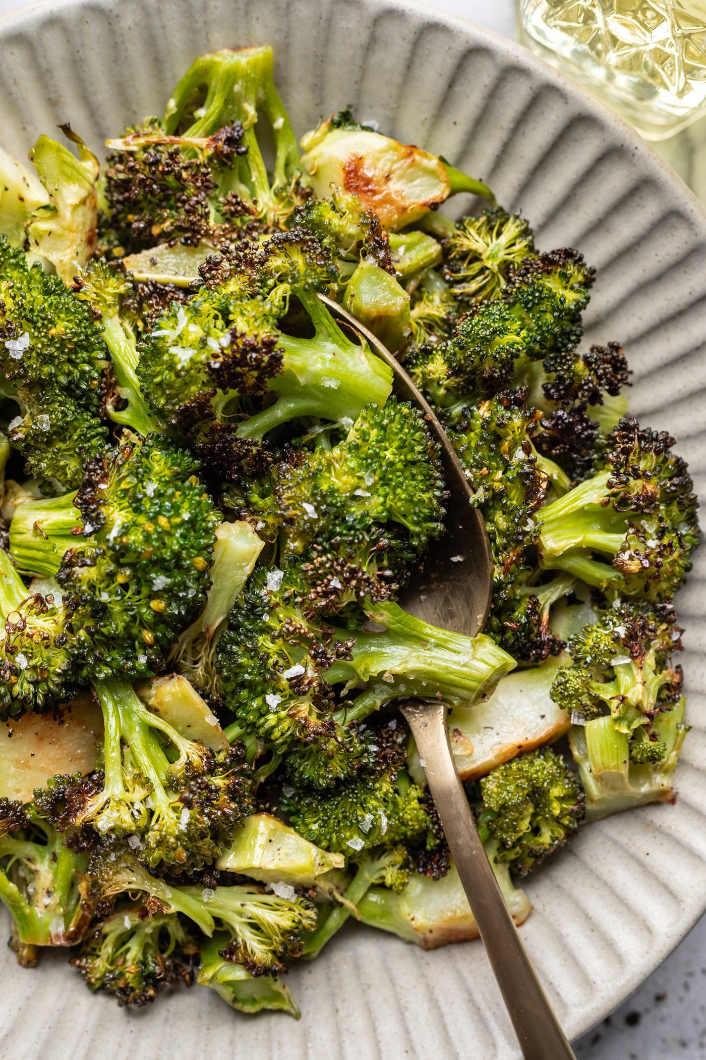 bowl of roasted broccoli with a serving spoon