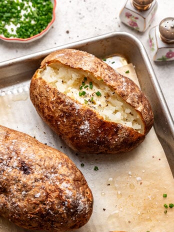 a baked potato open with butter and chives