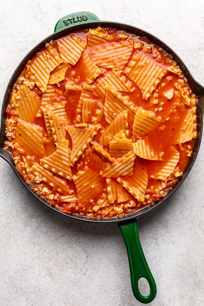 broken lasagna noodles in sauce in a skillet