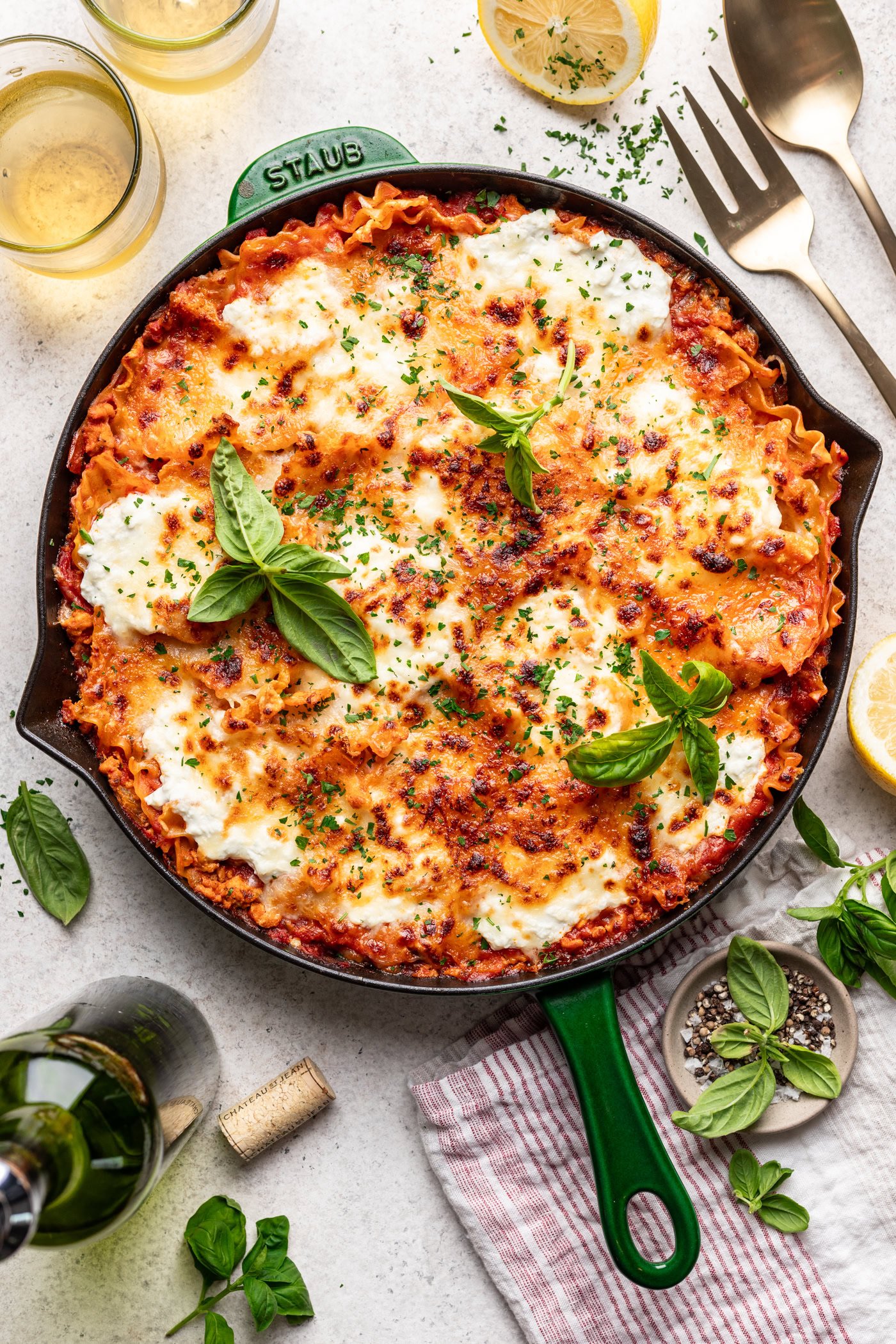 lasagna in a skillet with melted cheese and basil