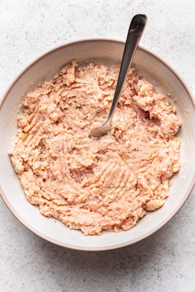 bowl of raw ground chicken with a fork