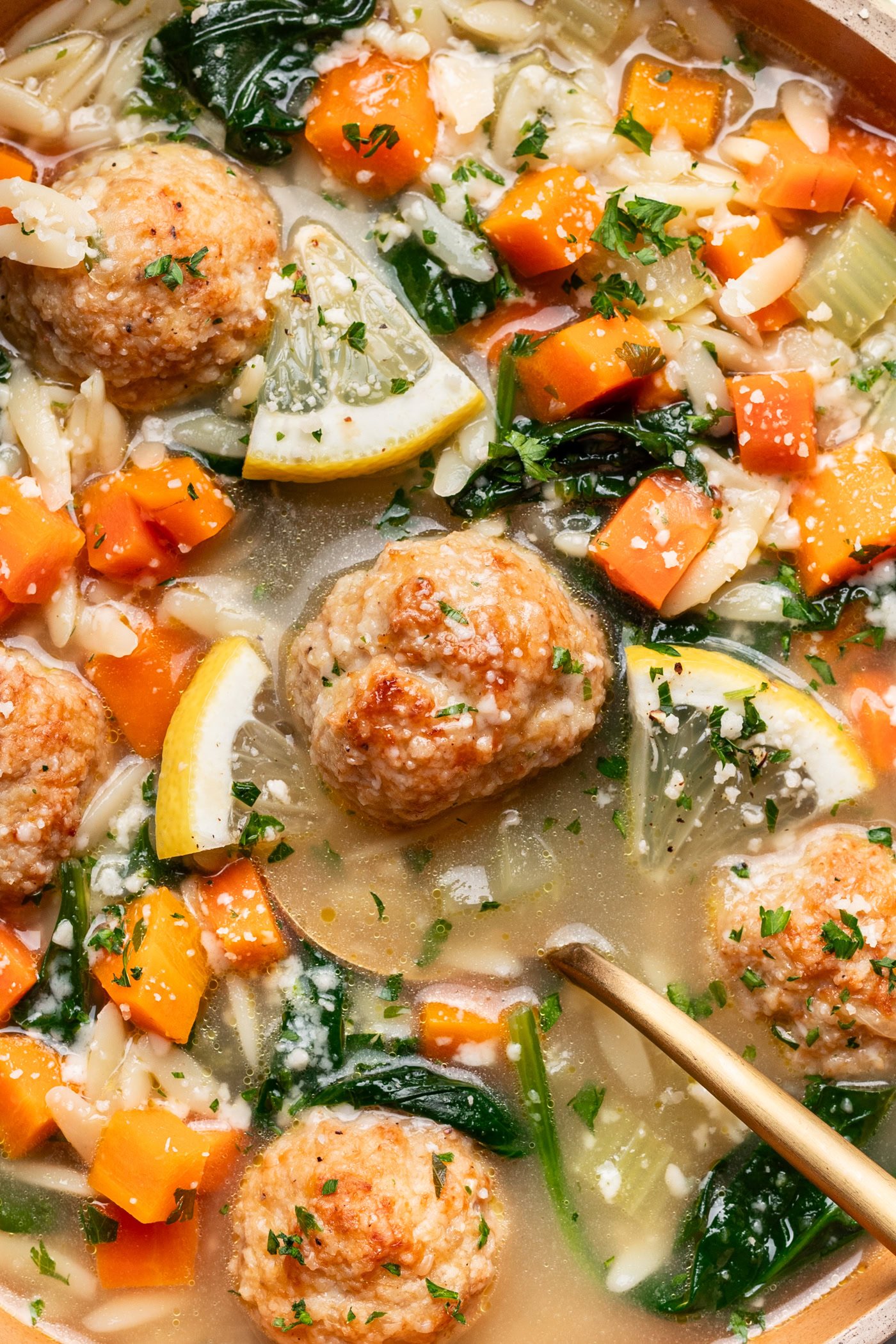 bowl of lemony chicken meatball soup up close with a spoon