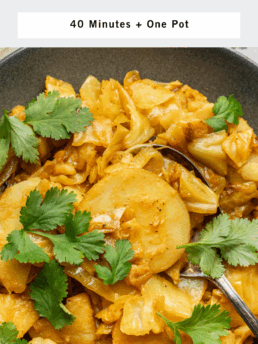 A bowl of turmeric cabbage and potatoes garnished with fresh cilantro, with a fork resting in the dish. The text above reads Turmeric Cabbage and Potatoes—40 Minutes + One Pot.