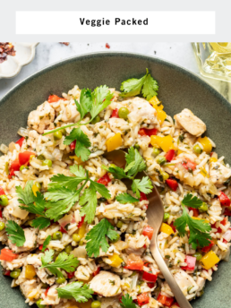 A bowl of chicken and cilantro rice with colorful vegetables, garnished with fresh cilantro, and a gold fork resting in the bowl. The text reads Chicken and Cilantro Rice, Veggie Packed, and Life is But a Dish.