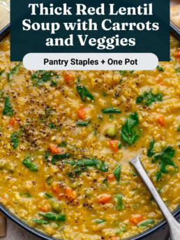 A bowl of thick red lentil soup with carrots, spinach, and spices sits on a marble surface with naan bread and a glass of white wine beside it. A spoon rests in the soup. Text overlay describes the dish.