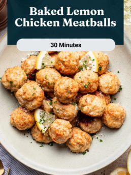 A bowl of baked lemon chicken meatballs garnished with parsley and lemon slices sits on a table with a fork, knife, lemon wedge, and pepper grinders nearby. Text reads: “Baked Lemon Chicken Meatballs, 30 Minutes.”.