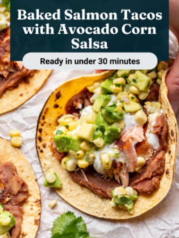 A close-up of baked salmon tacos topped with avocado corn salsa, served on corn tortillas with refried beans. Fresh lime and cilantro garnish are visible, with a label reading “Baked Salmon Tacos with Avocado Corn Salsa.”.